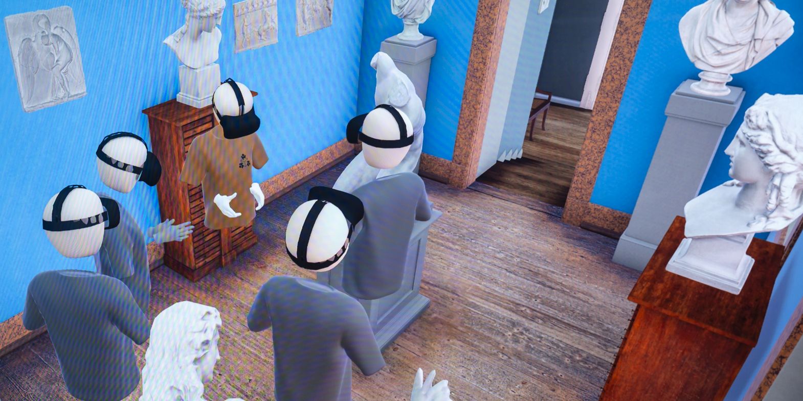 Das Bild zeigt eine virtuelle Szene in einem Raum mit blauen Wänden und einem Holzboden. Mehrere Avatare, die VR-Headsets tragen, stehen in der Mitte des Raumes. Um sie herum befinden sich verschiedene Statuen und Büsten auf Sockeln. An den Wänden hängen gerahmte Bilder und Skizzen. Im Hintergrund ist eine Treppe zu sehen, die nach oben führt, sowie eine offene Tür, die in einen anderen Raum führt. Die Szene wirkt wie eine virtuelle Kunstgalerie oder ein Museum.