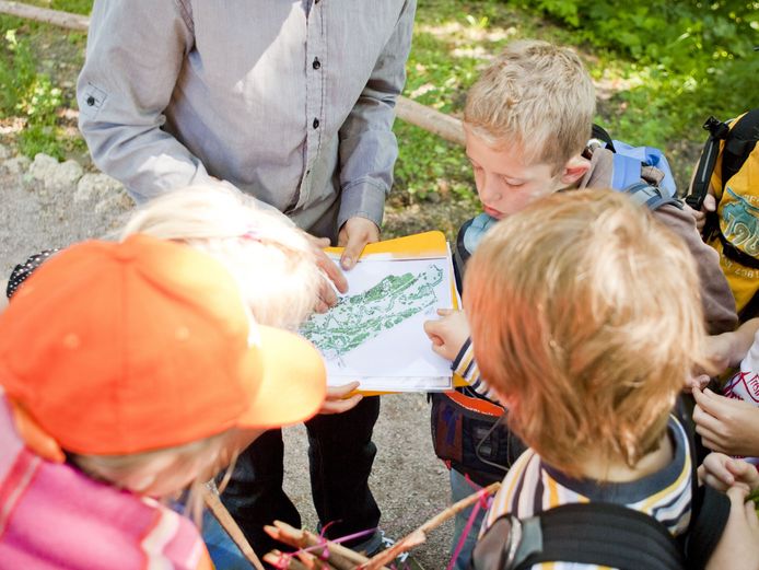 Ein Erwachsener zeigt einer Gruppe von Kindern eine Karte des Ilmparks