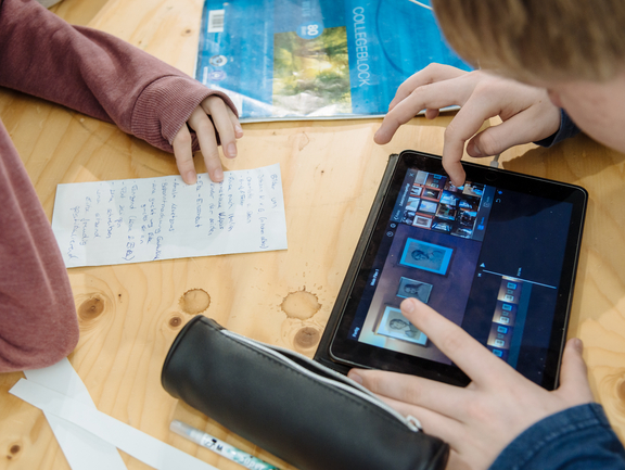 Zwei Jugendliche schneiden ihren Film am Tablet.