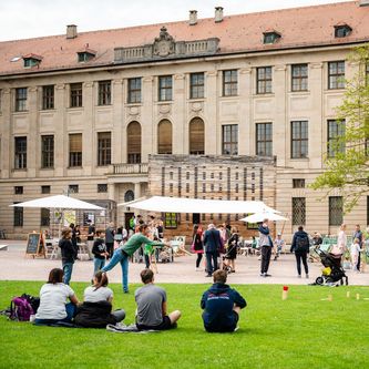 Menschen genießen die Wiese und Aktionen des Co-Labors vor dem Weimarer Schloss.