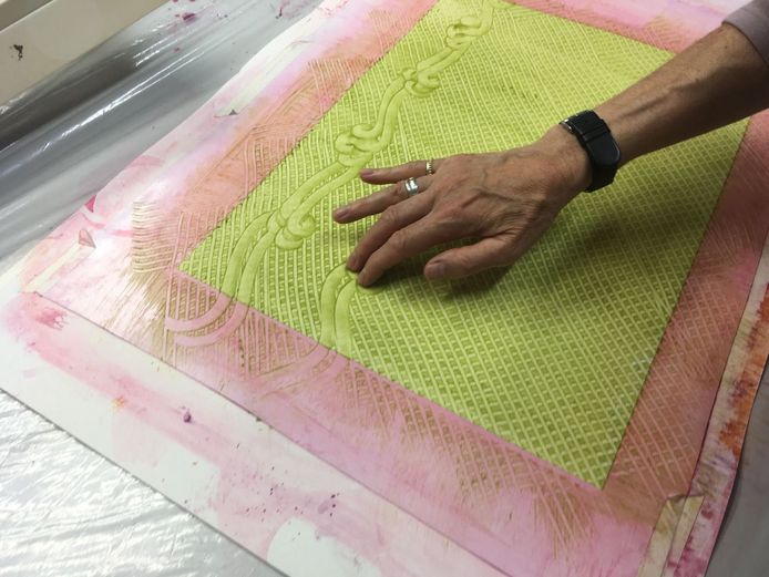 Die Fotografie zeigt, wie ein Kleisterpapier von der Buntpapiermacherin Susanne Krause mit den Händen verziert wird. Der Kleisterpapierkurs fand im Rahmen der Buchbinderausbildung im Jahr 2018 statt.