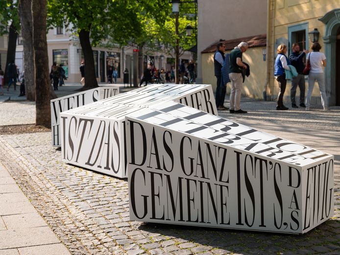 Drei Wortskulpturen stehen im Vordergrund vom Schiller Wohnhaus, in das Museumsbesucher eintreten