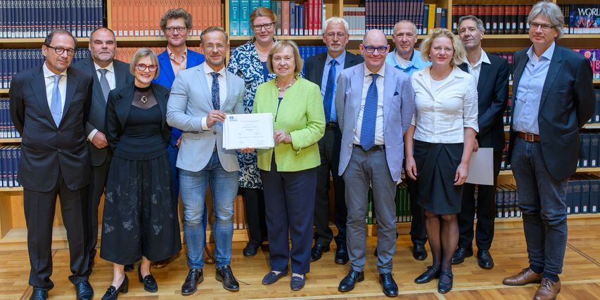 Übergabe der UNESCO-Urkunde „Memory of the World“ für Nietzsches Nachlass Auf dem Bild steht eine Gruppe von enschen und zeigt die UNESCO-Urkunde. Zu sehen sind v.l.n.r.: Prof. Dr. Urs Saxer, Präsident der Stiftung Nietzsche-Haus in Sils; Prof. Dr. Steffen Teichert, Staatssekretär im Thüringer Ministerium für Bildung, Wissenschaft und Kultur; Dr. Ulrike Lorenz, Präsidentin der Klassik Stiftung Weimar; Prof. Dr. Helmut Heit, Klassik Stiftung Weimar; Dr. Christian Hain, Direktor des Goethe- und Schiller-Archivs Weimar; Katharina Ribbe, Auswärtiges Amt, Referentin für Multilaterale Kulturpolitik, Kulturgutschutz, Rückführungsfragen; Prof. Dr. Maria Böhmer, Präsidentin der Deutschen UNESCO-Kommission; Prof. Dr. Konrad Elmshäuser, Vorsitzender des Deutschen Nominierungskomitees „Memory of the World“; Dr. Lorenz Heiligensetzer, Geschäftsführer der Universitätsbibliothek der Universität Basel; Dr. Noah Regenass, Universitätsbibliothek Basel; Dr. Annette Ludwig, Direktorin der Direktion Museen der Klassik Stiftung Weimar; Prof. Dr. Hubert Thüring, Universität Basel; Dr. Reinhard Laube, Direktor der Herzogin Anna Amalia Bibliothek Weimar.