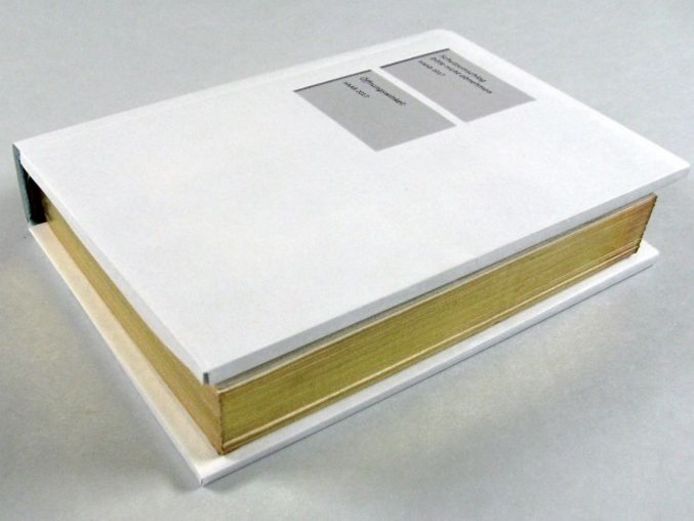 Dargestellt ist ein Buch mit einem weißen Schutzumschlag. Er schützt den Einband aus Seide oder Seidensamt.