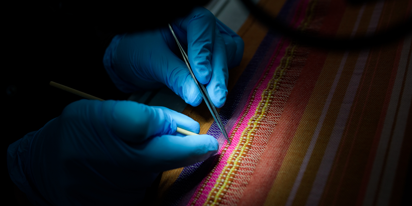 A conservator works on restoring a rug in the textile workshop