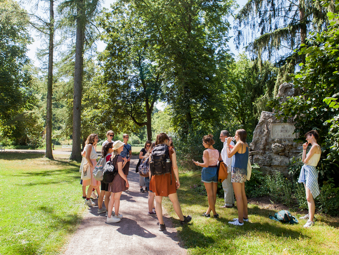 Group of young adults standing in a circle around the memorial stone for Herder